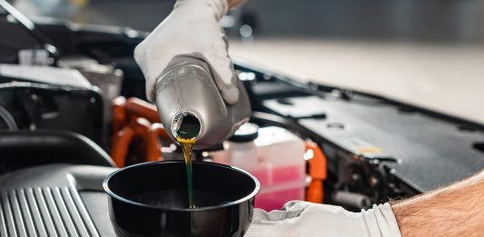 cropped view of mechanic pouring oil to car engine