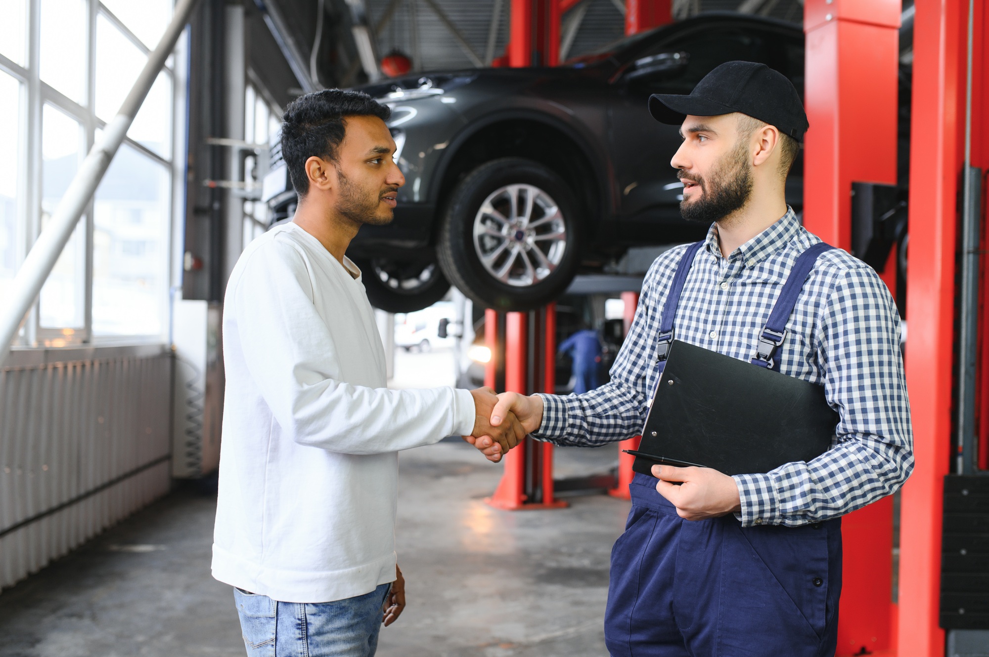 A mechanic in a car service is talking to an Indian car owner. Car service concept