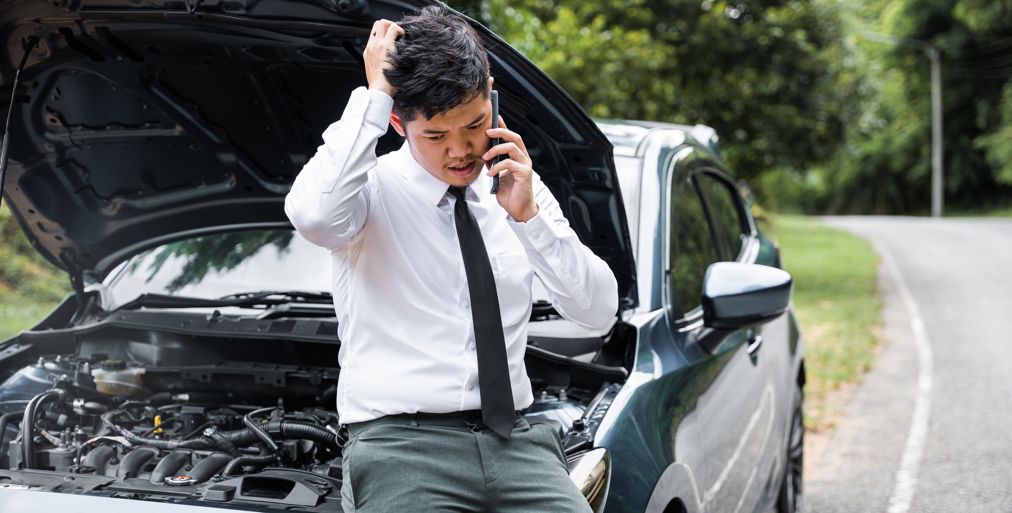 Asian businessman stranded on the road after car breakdown