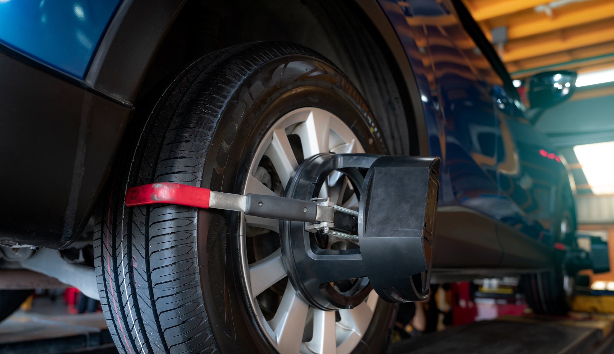 Wheel alignment equipment grip the tire of car wheel in car repair shop. Auto wheel alignment