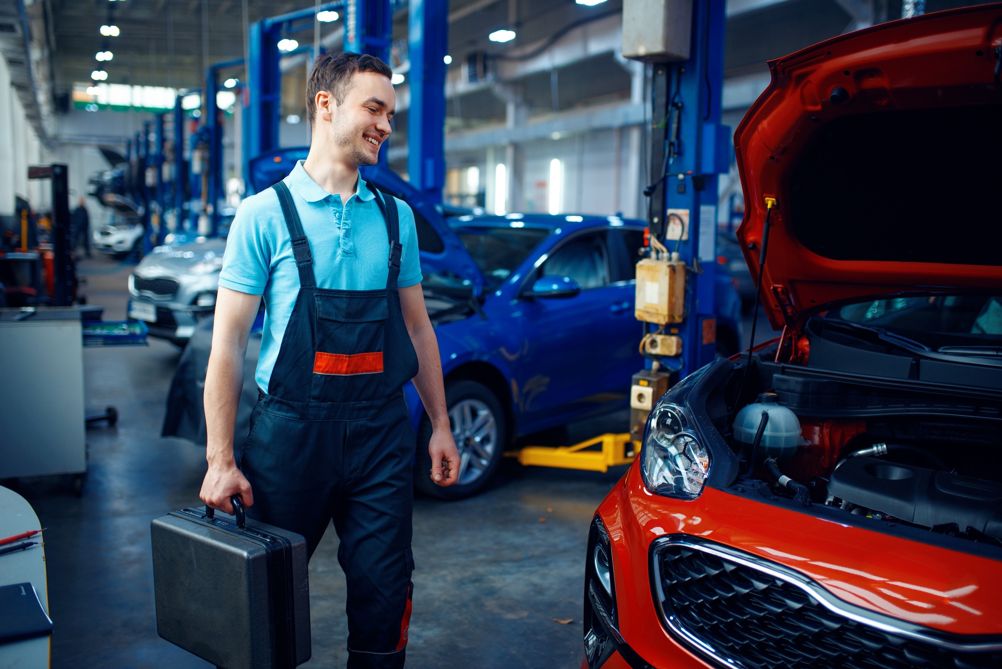 Worker holds a toolbox, car service station