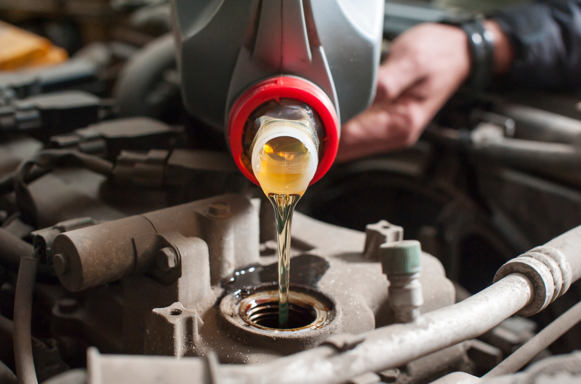 a man pours oil into a car engine close-up