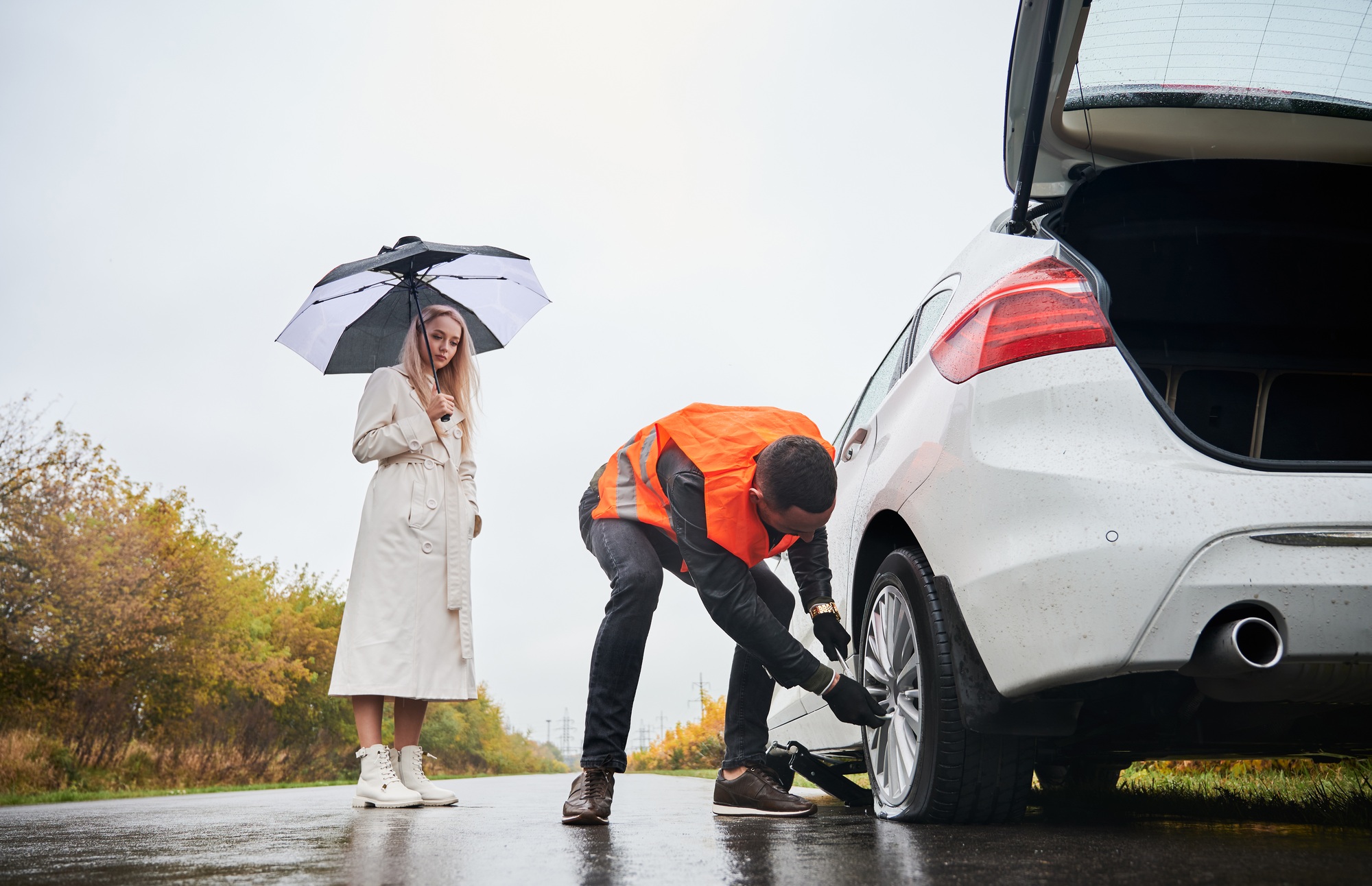 Roadside assistance worker repairing woman vehicle on the street.