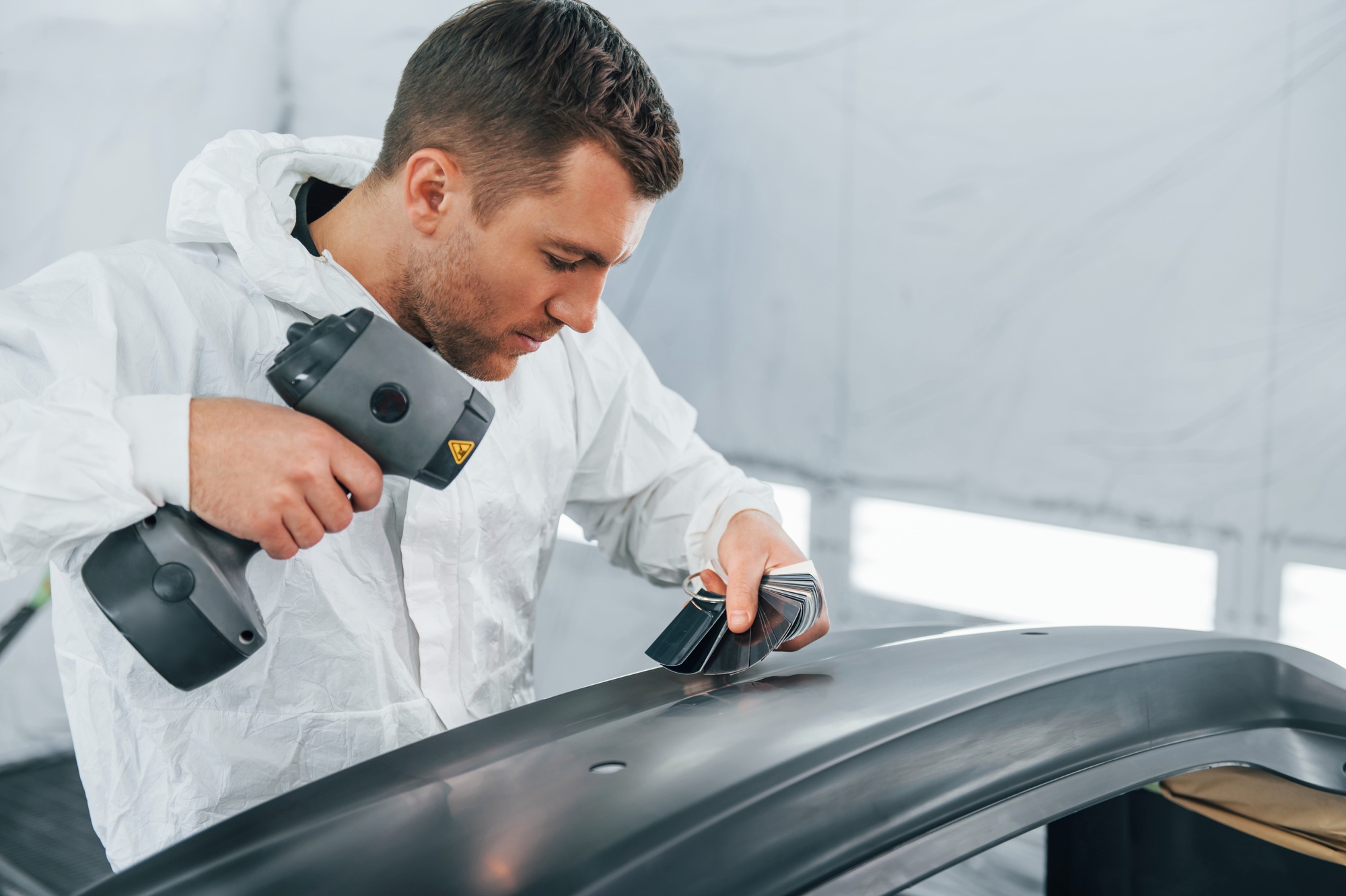 Working with car surface. Man in uniform is working in the auto service